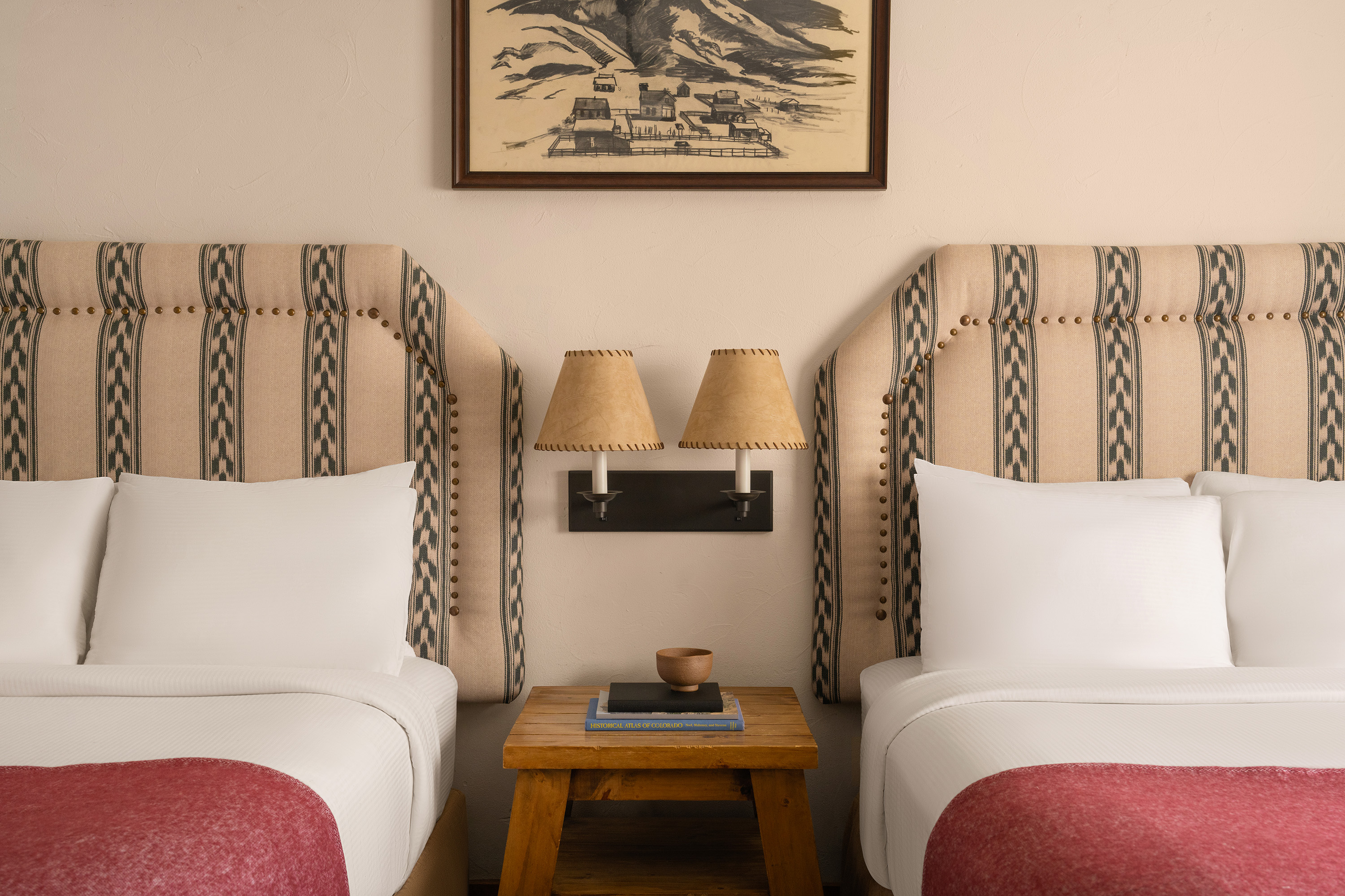 A hotel room with two beds, a nightstand, and a picture on the wall.