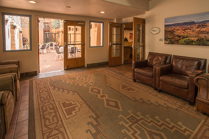 A hotel lobby with leather sofas, a patterned rug, and artwork on the walls.