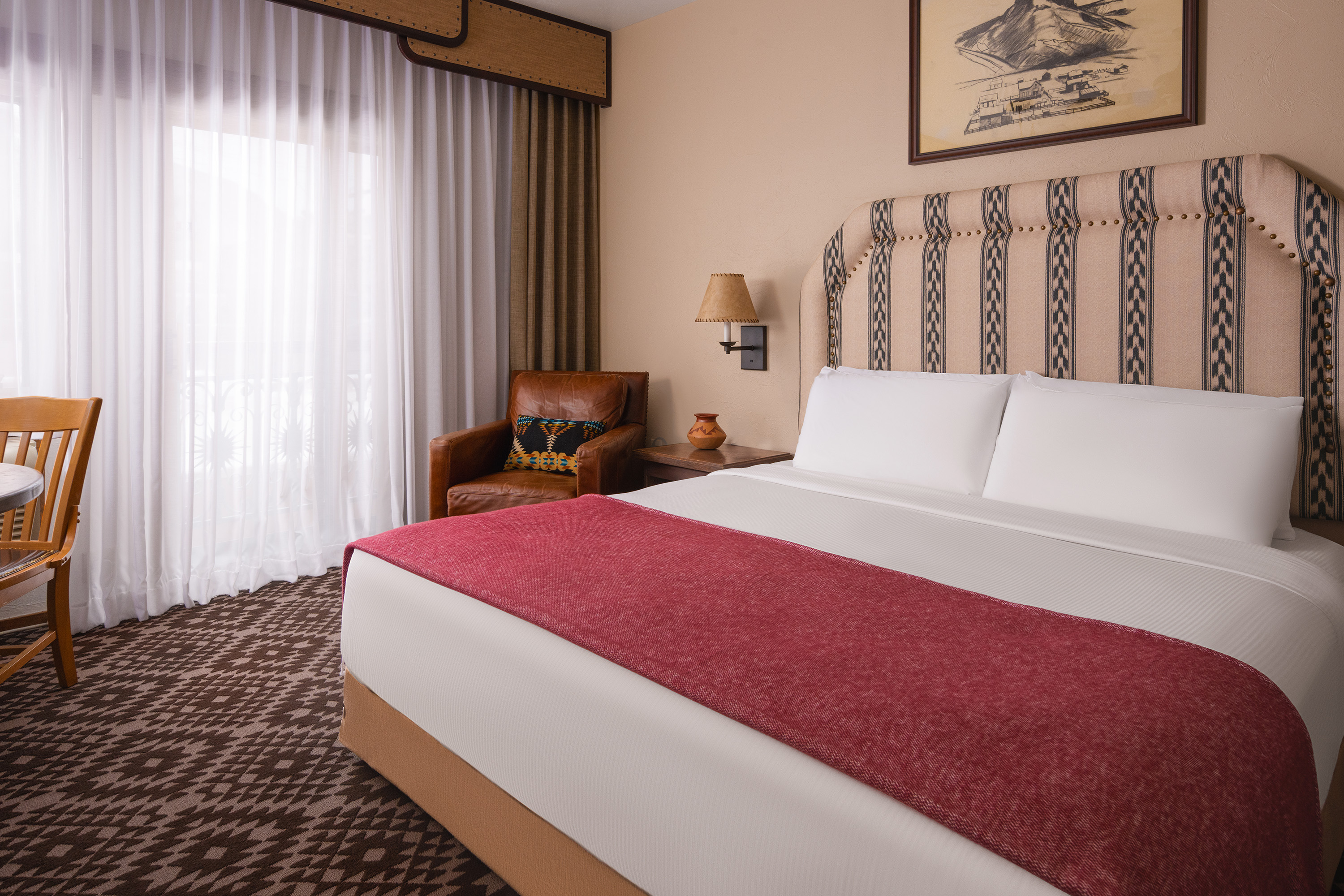 A hotel room with a large bed, comfortable seating, and a window.