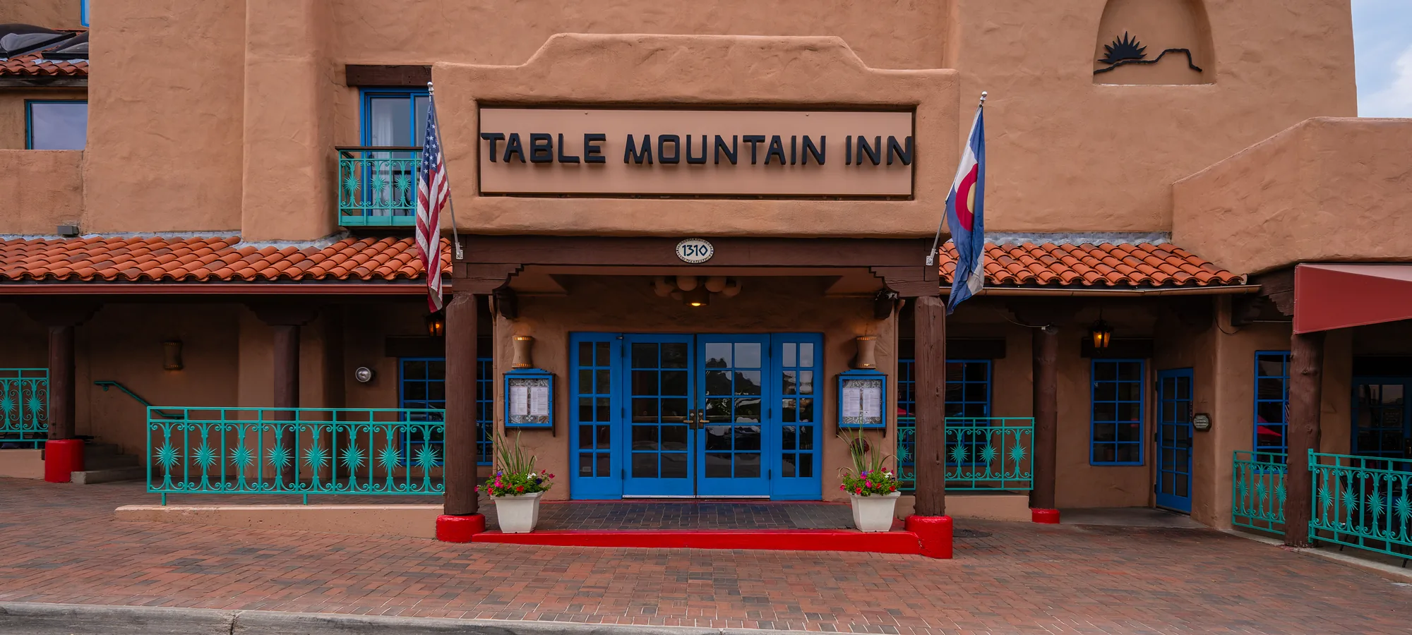 Table Mountain Inn entrance in Golden, Colorado Adobe front entrance of Table Mountain Inn in Golden, Colorado, with the hotel sign, blue doors, and American and Colorado flags