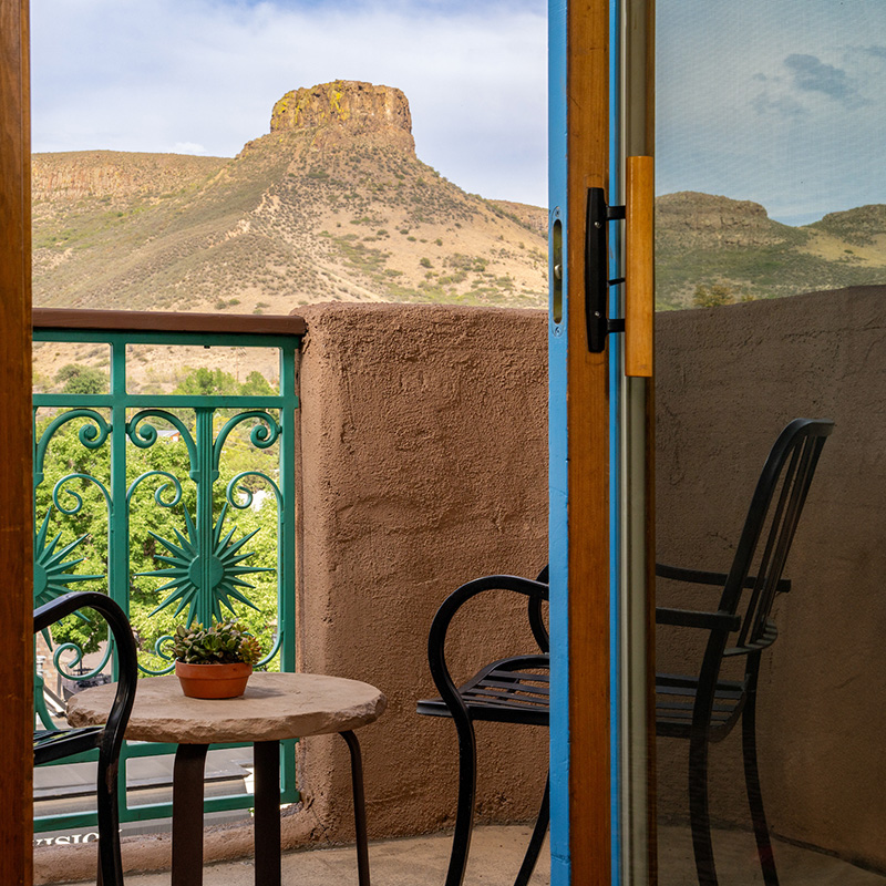A balcony with a table and chairs overlooking a mountain